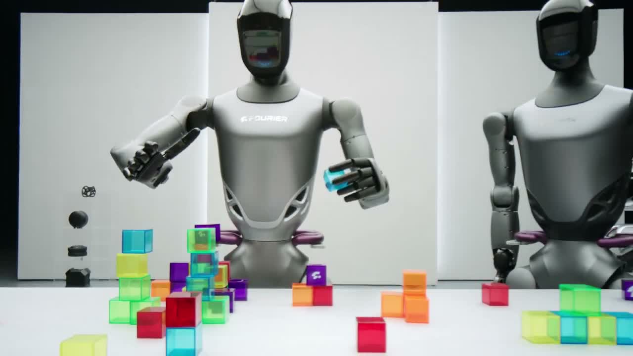 Fourier GR-2 humanoid robot manipulating coloured blocks on a table in a studio. Still from the official Fourier video "Say hello to GR-2!" (2024).